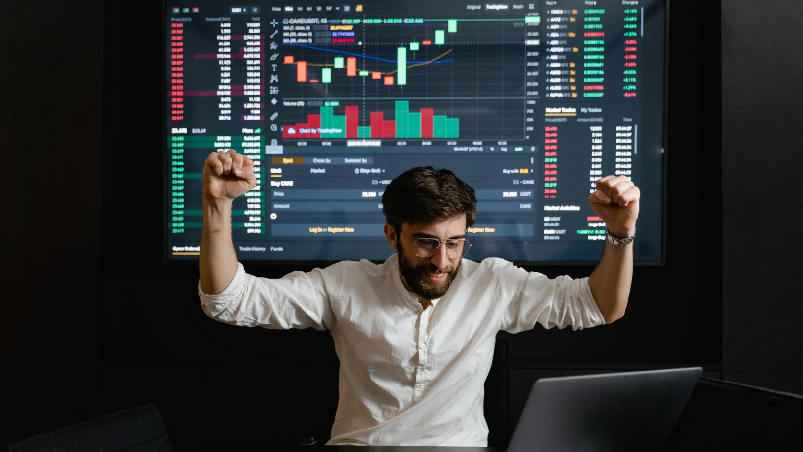 Trader celebrating in front of trading screens